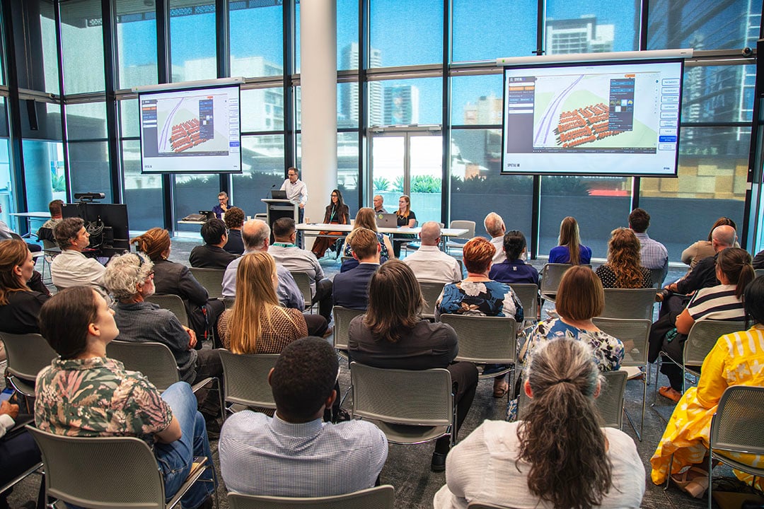 Spatial WA formally presenting a use case scenario, showing a 3D virtual environment on screen, to an interested crowd.